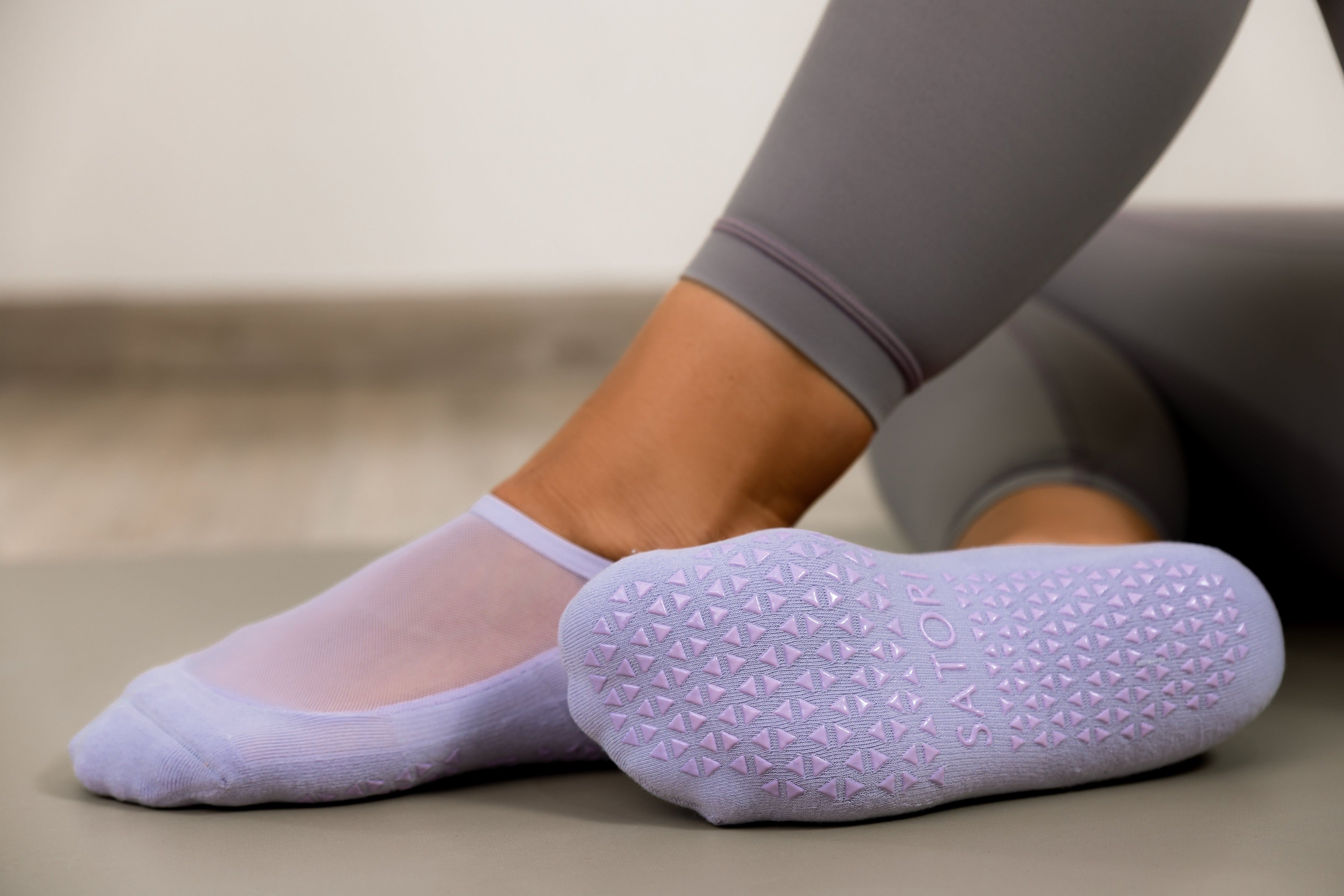 Close-up of pink Satori ballet grip socks with crisscross straps during aerial yoga, showing soft texture and non-slip design.