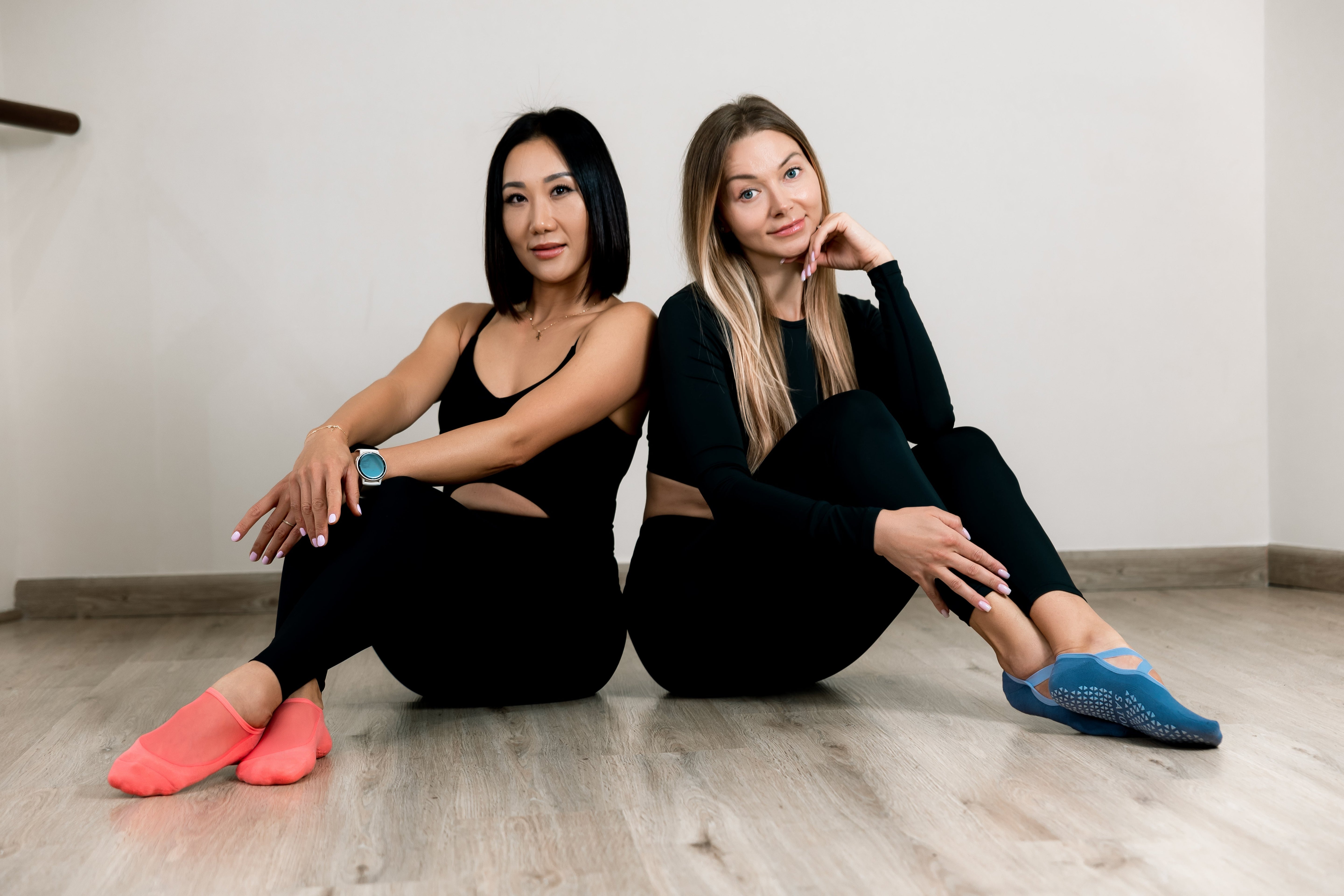 Women wearing pastel Satori grip socks during aerial yoga in studio, showcasing new arrivals designed for balance and movement.