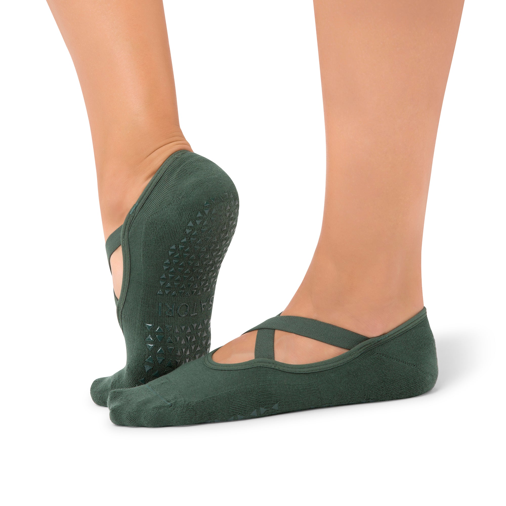 Dark-toned Naomi Mystic Jade grip socks with cross straps worn in a UAE yoga studio